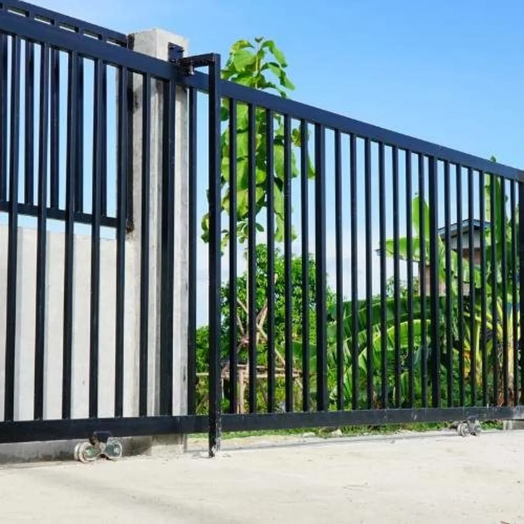 Bir tesis girişindeki sürgülü siyah metal kapı ve panel çit